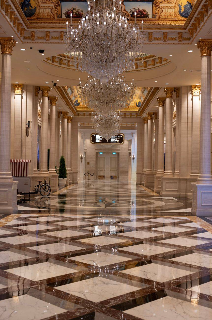 Elegant hall with chandeliers and marble flooring in a Macao casino resort, showcasing opulent interior design.