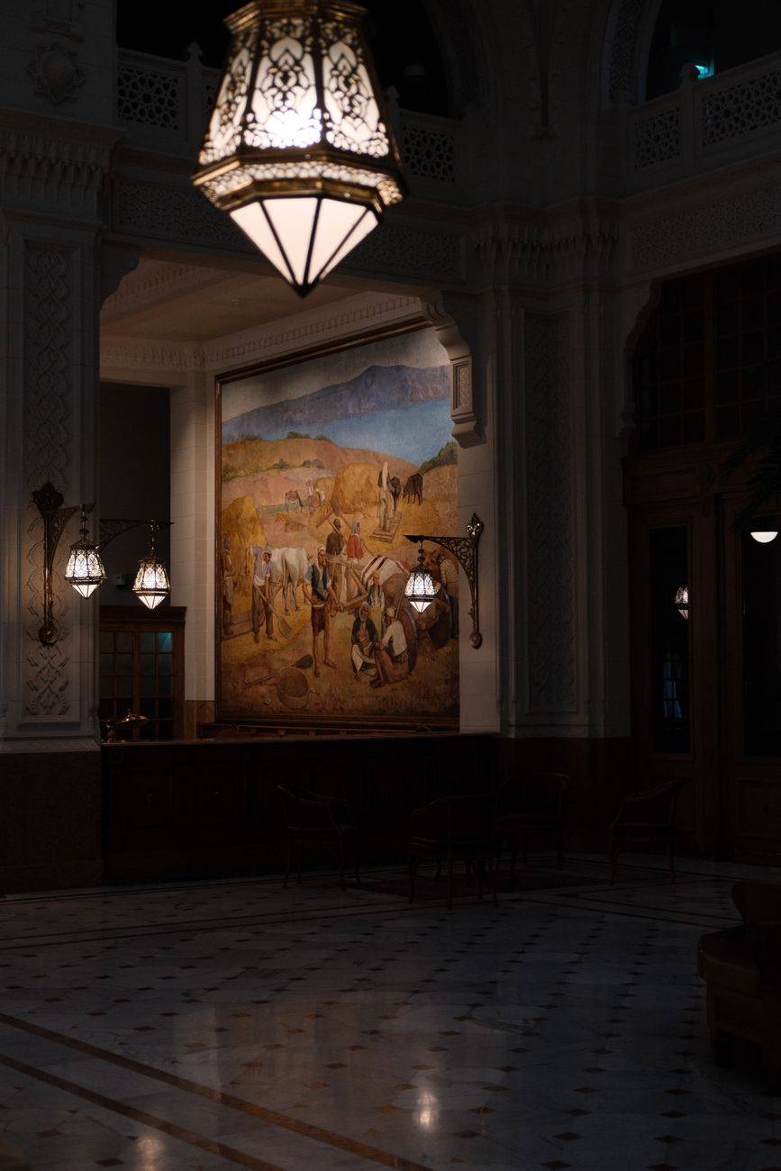 Sophisticated interior with ornate lighting and a large mural depicting historical scenes.