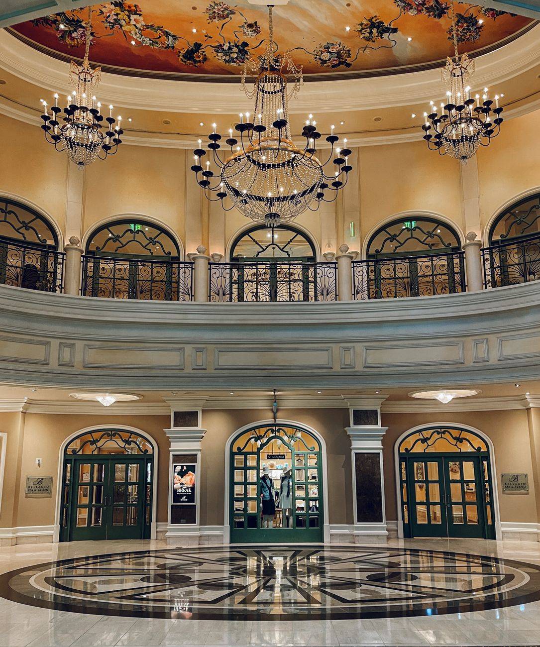 Opulent hotel lobby featuring grand chandeliers and intricate ceiling art, showcasing elegance and luxury.