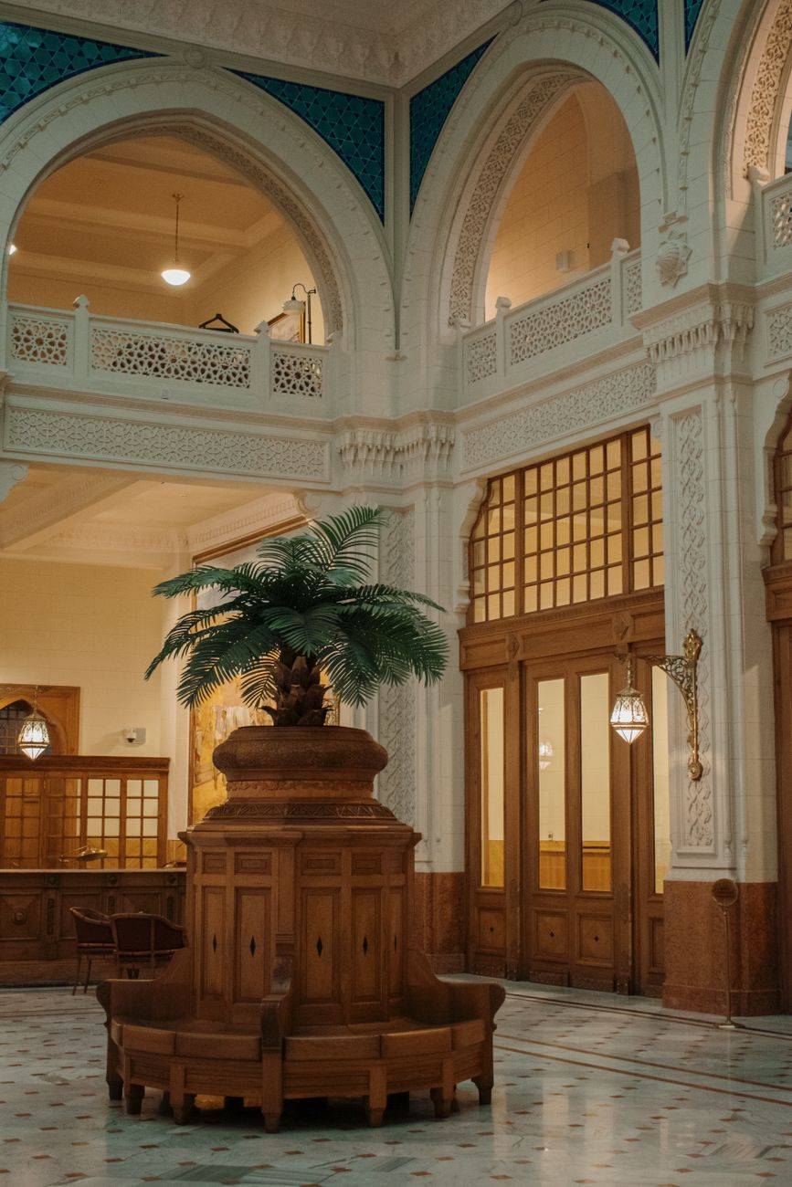 Luxurious hotel lobby featuring arched designs, wooden accents, and a central palm display.