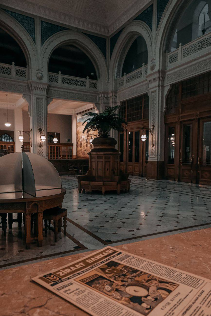 Elegant bank lobby with vintage decor and newspaper on table.