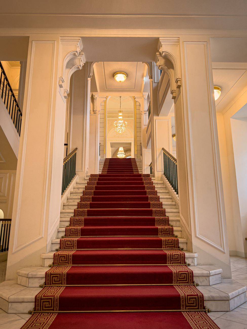 Majestic staircase with red carpet in a classic Vienna building interior.
