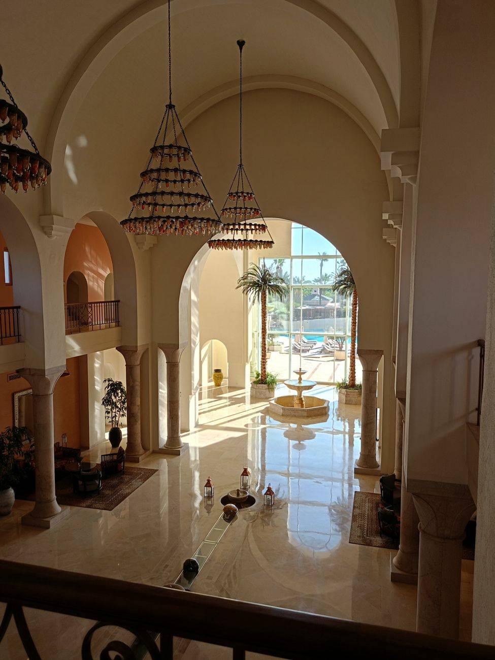 Elegant hotel lobby featuring marble flooring, grand chandeliers, and a view of the pool.