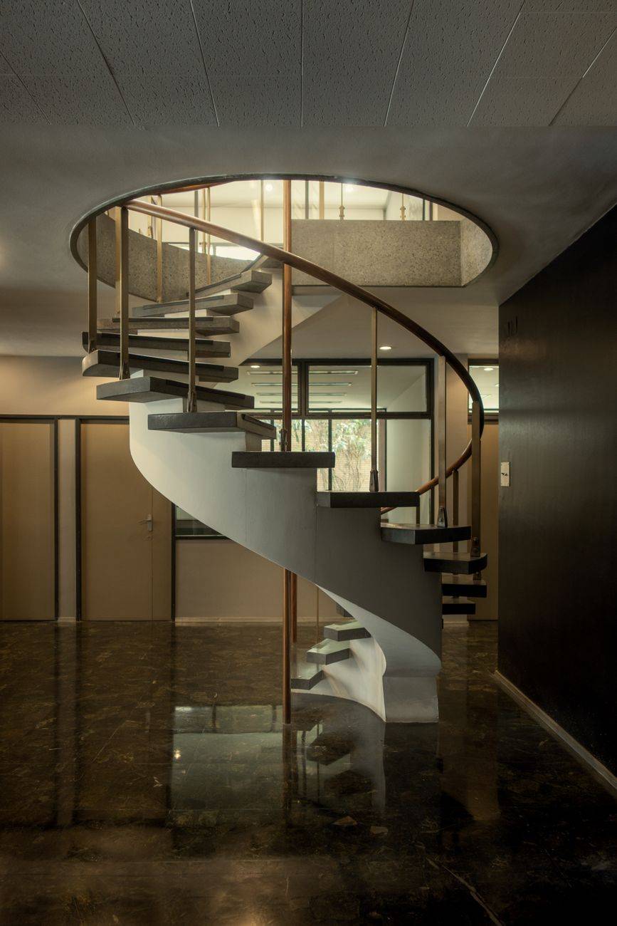 Elegant indoor spiral staircase with modern design and reflections on shiny floor.
