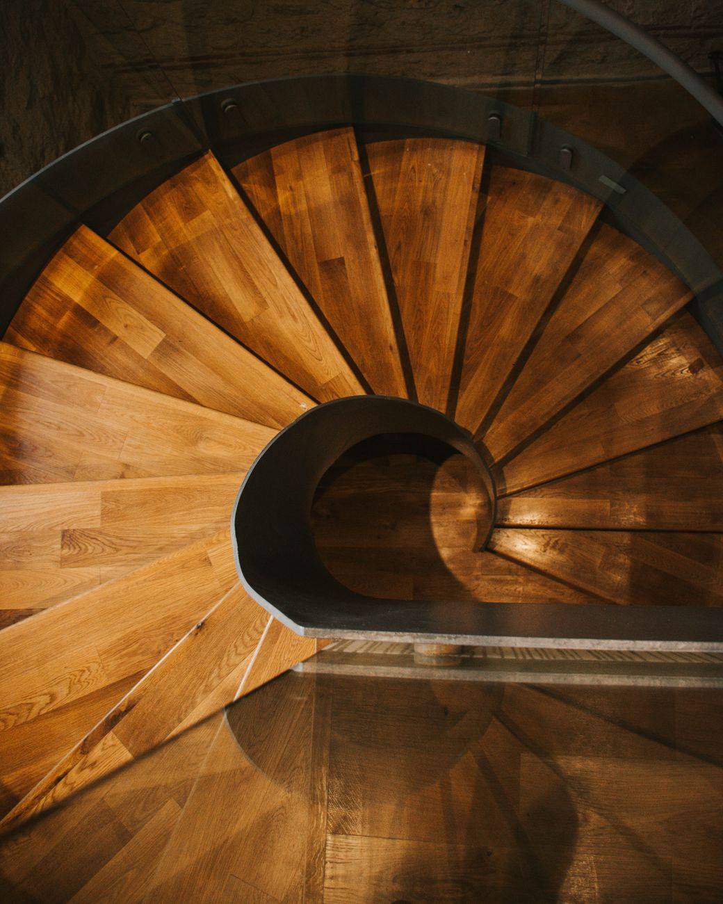 Top view of a beautifully crafted wooden spiral staircase, showcasing intricate design and rich texture.