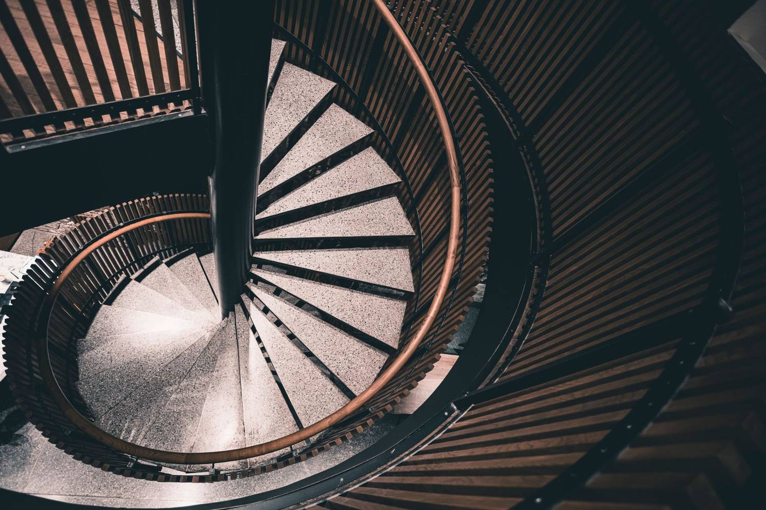 Modern spiral staircase with intricate railings captured from above, showcasing architectural beauty.