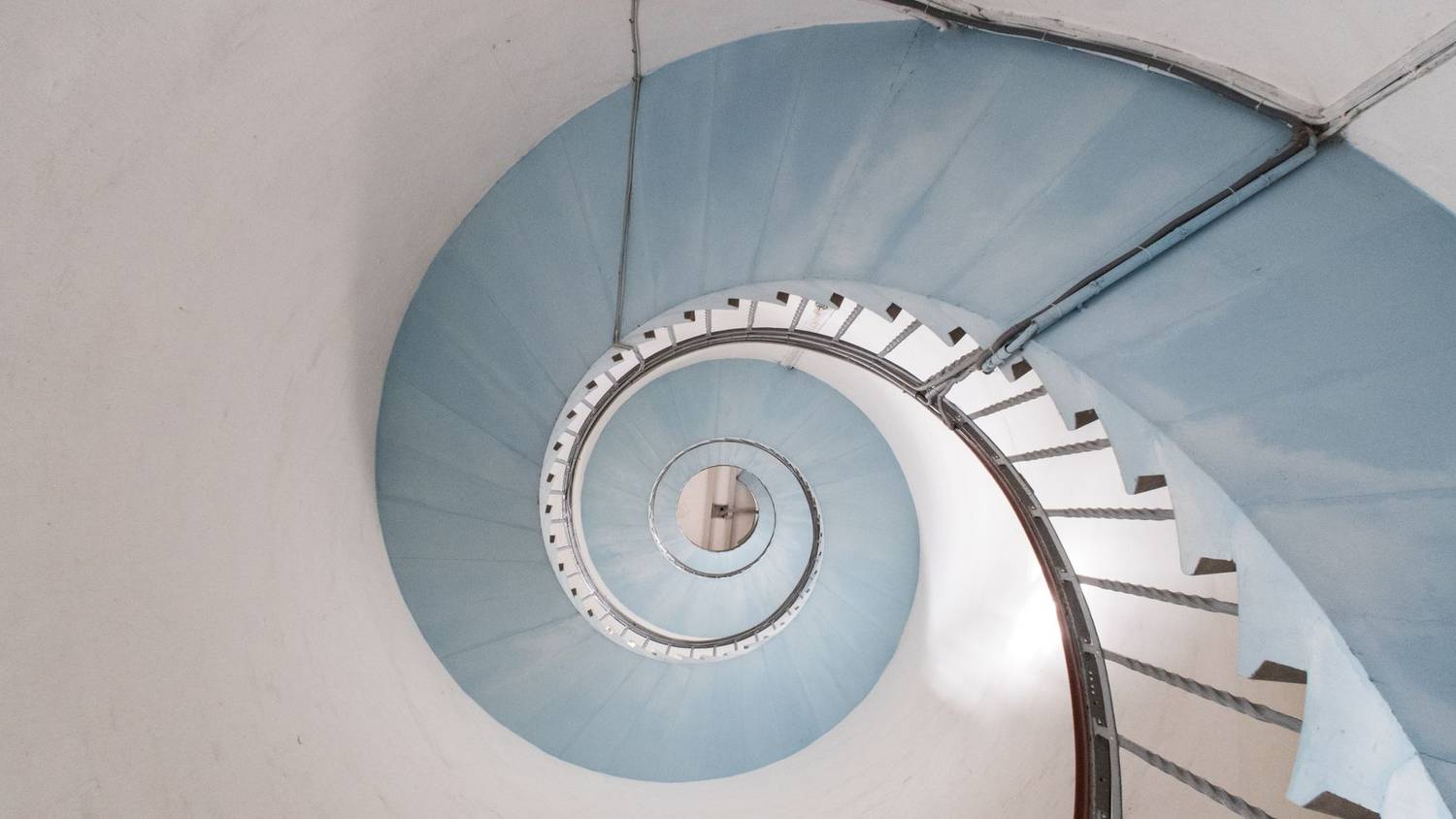 View from above of a blue spiral staircase in a lighthouse.