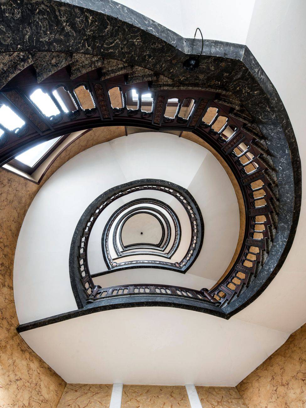 Intricate spiral staircase with perspectives and symmetry inside a building in Hamburg.