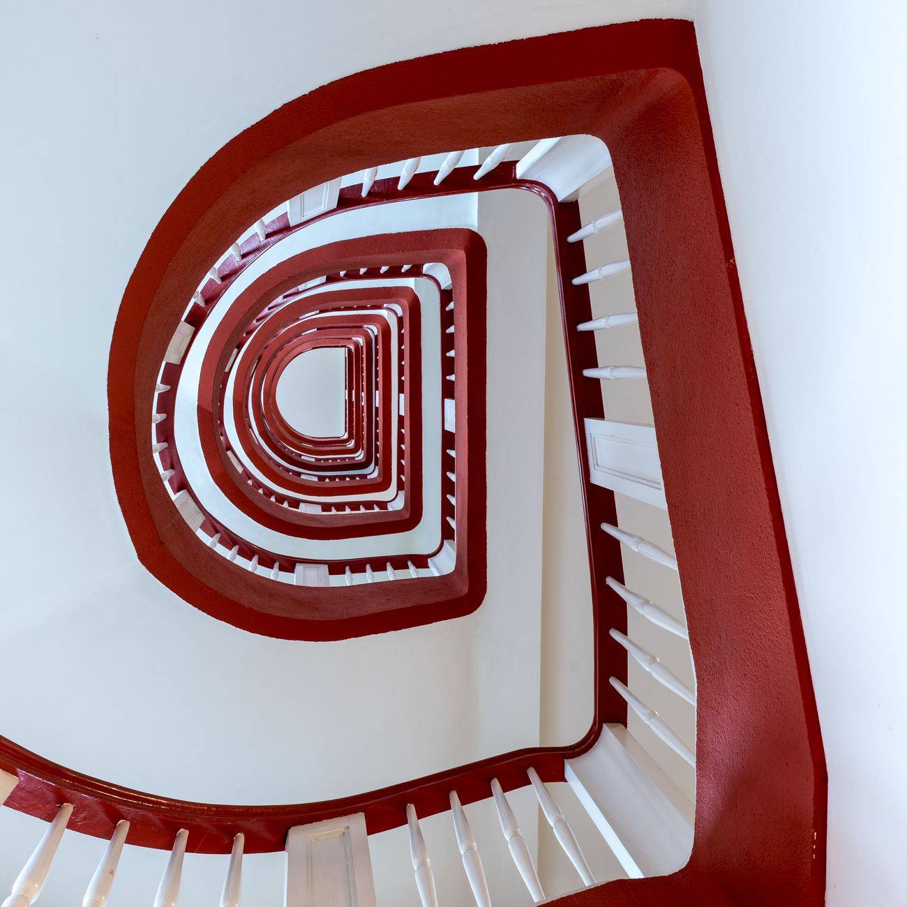 A mesmerizing view of a spiral staircase with vibrant red railings in Hamburg, Germany.