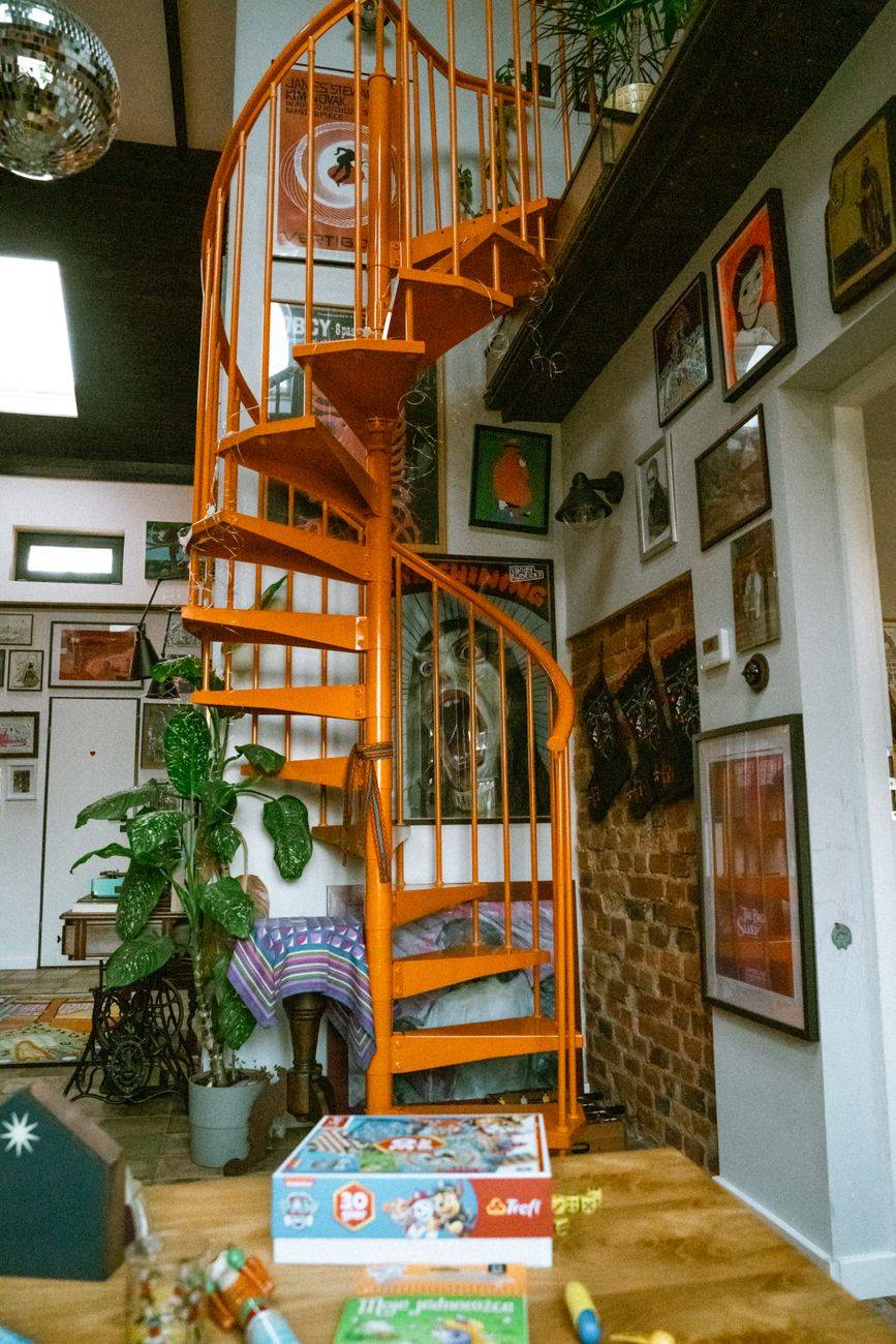 A vibrant orange spiral staircase in a creatively decorated interior space.