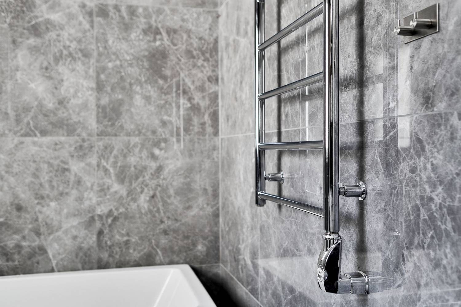 Contemporary bathroom featuring marble walls and a sleek steel towel rail.