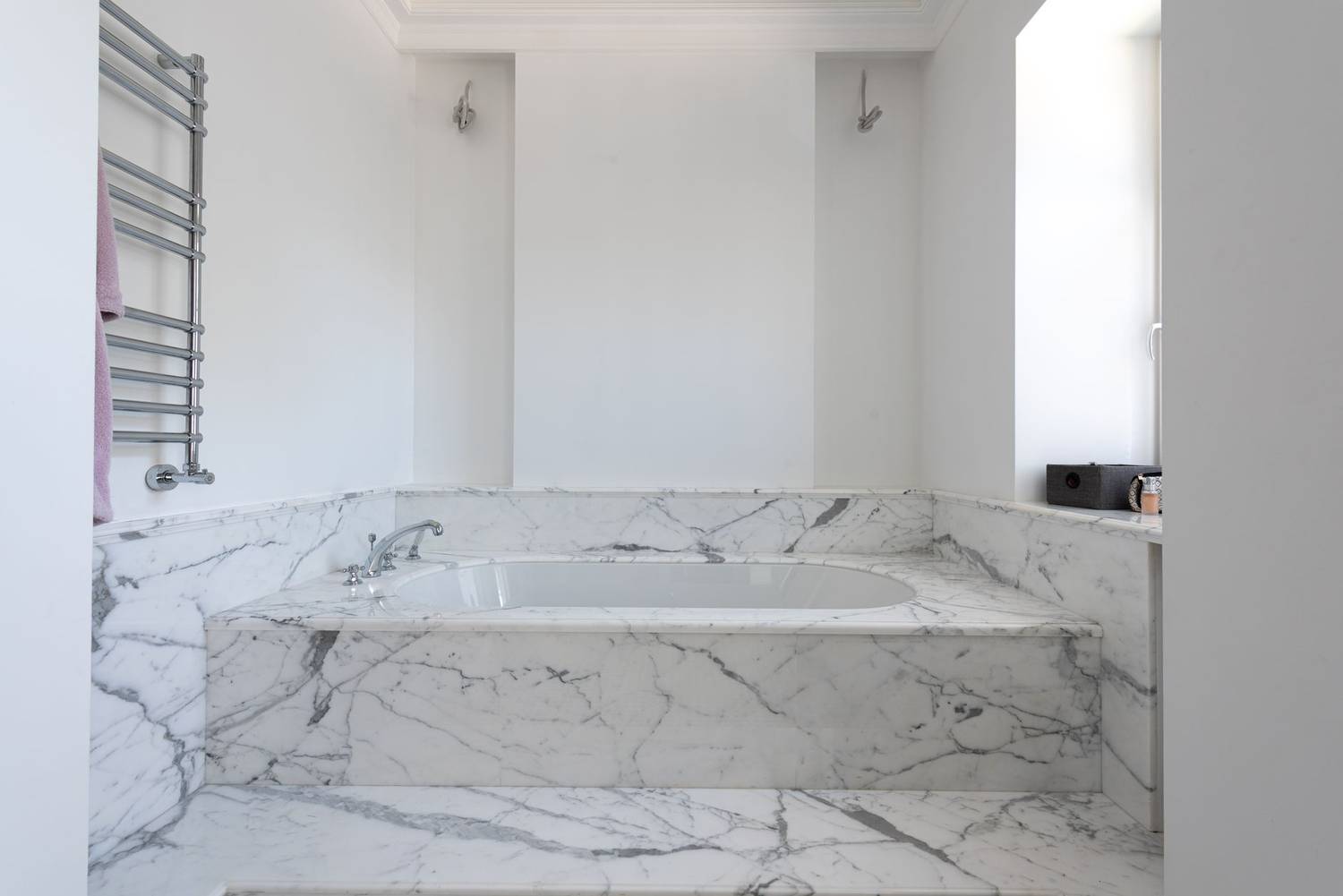 Modern bathroom with a luxurious marble bathtub and chrome fixtures.