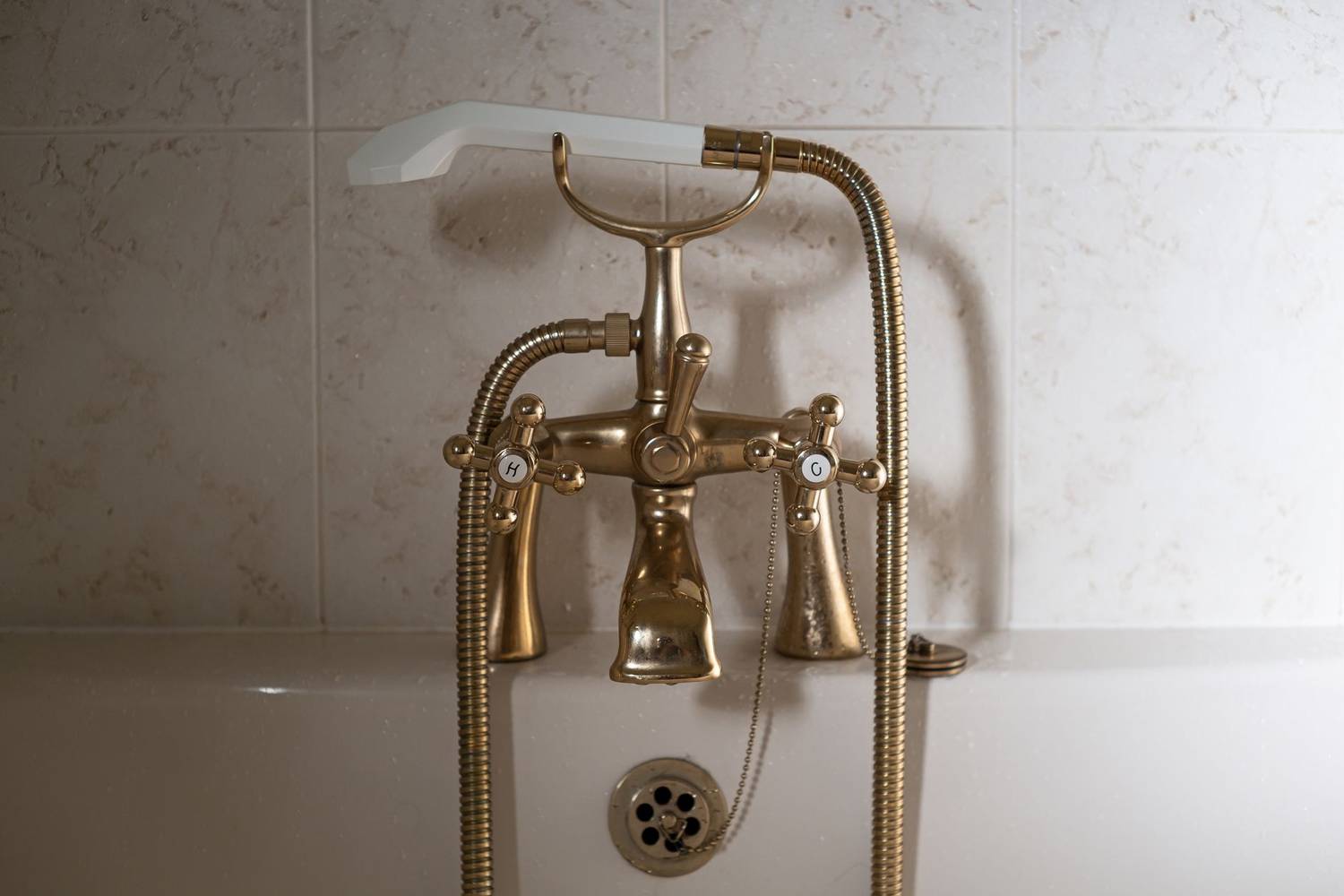 Close-up of a classic brass bathtub faucet with a ceramic hand shower in Greystoke, England.