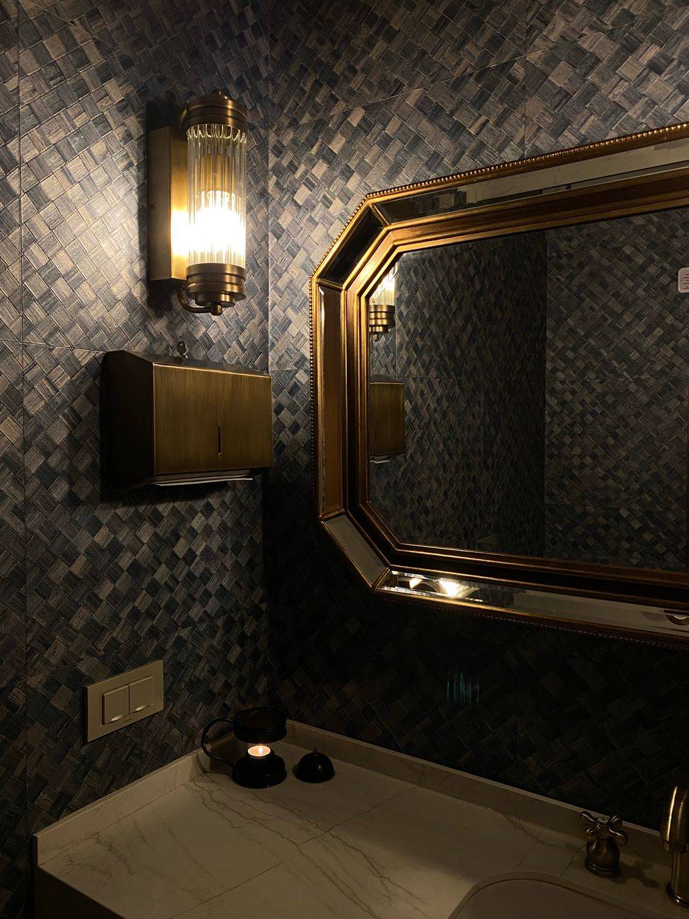 Stylish bathroom interior featuring geometric tiles, modern mirror, and warm lighting for a cozy ambiance.