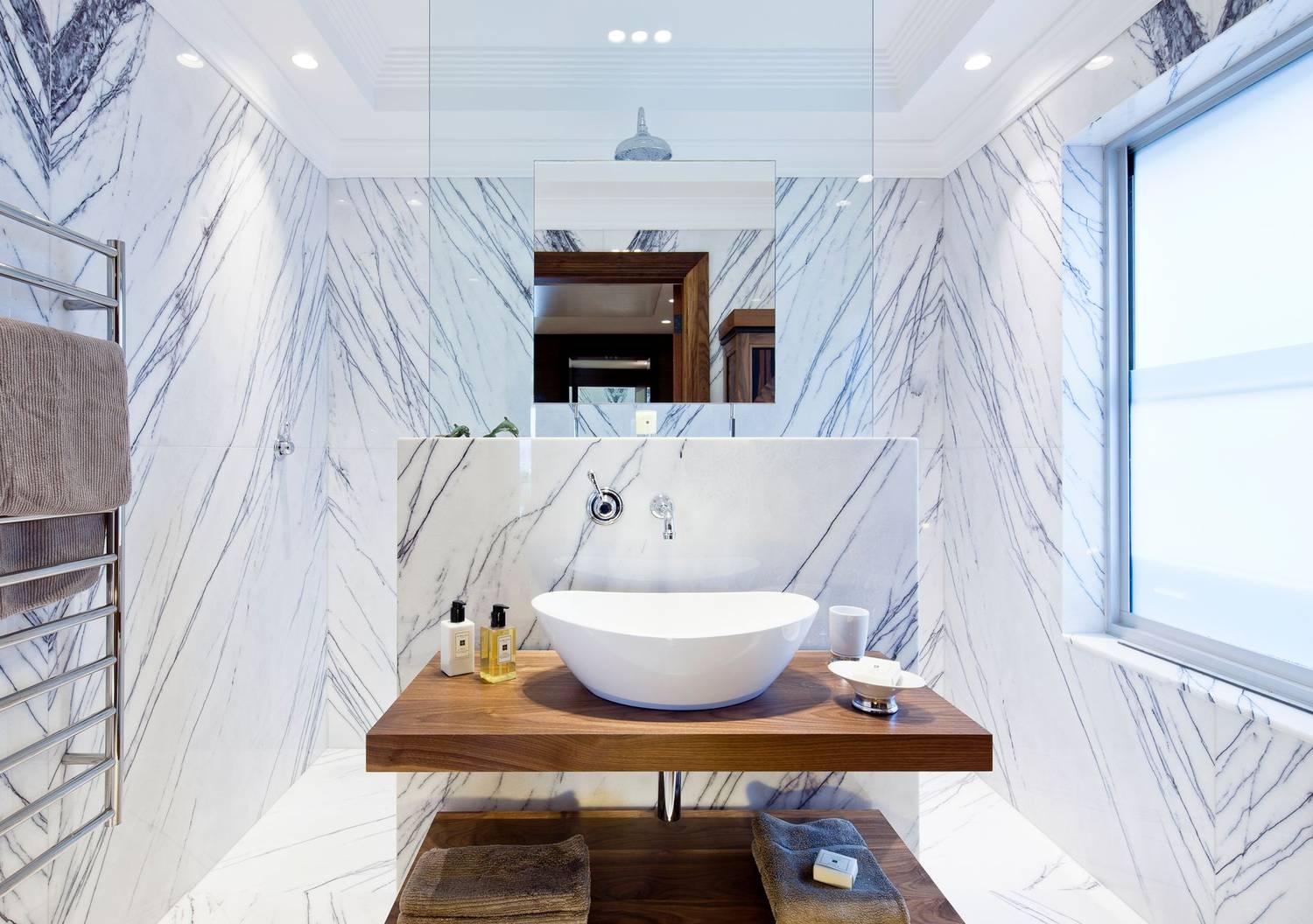 Contemporary bathroom design featuring marble walls and modern sink.