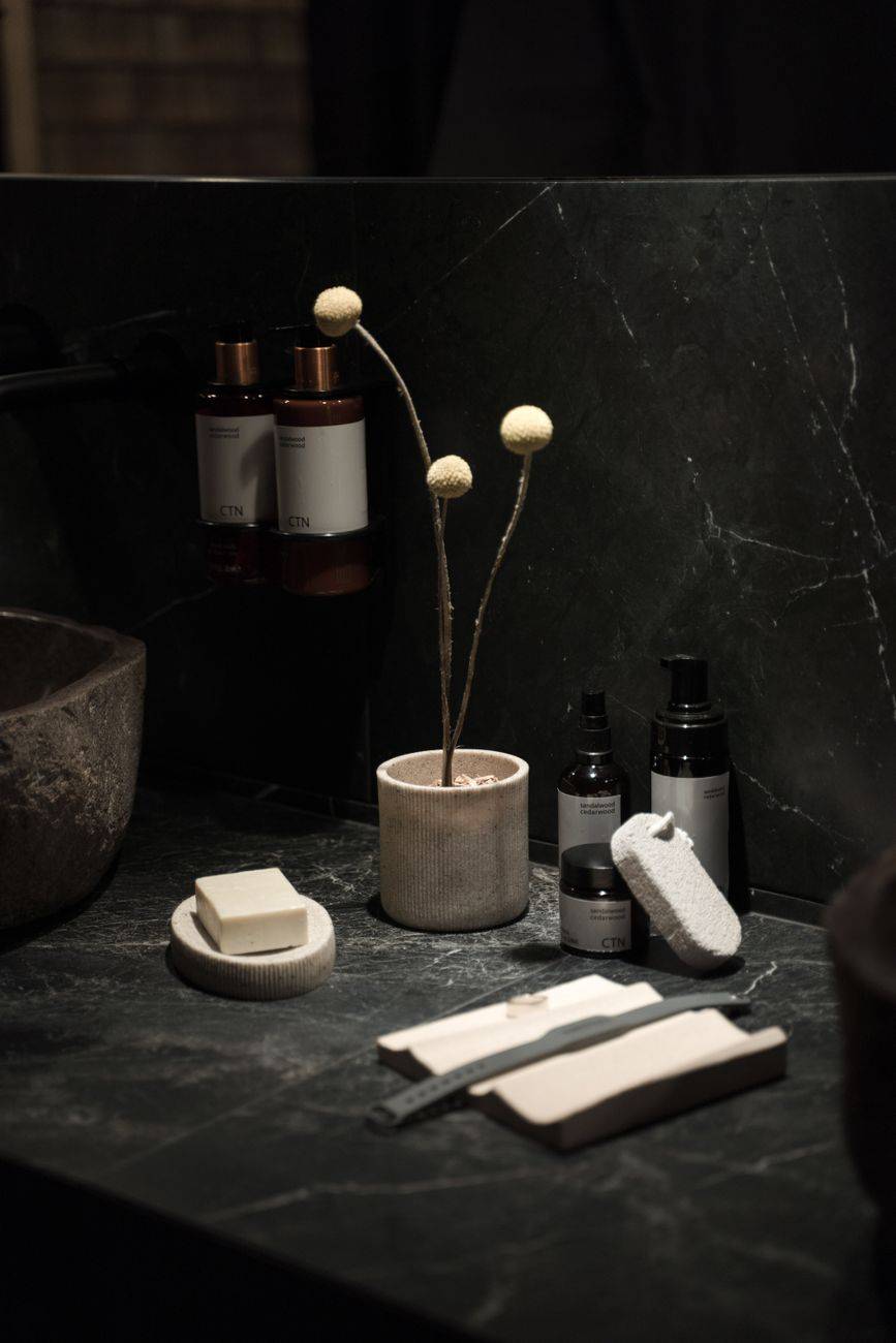 A stylish bathroom setup showcasing elegant toiletries and modern decor on a dark marble counter.