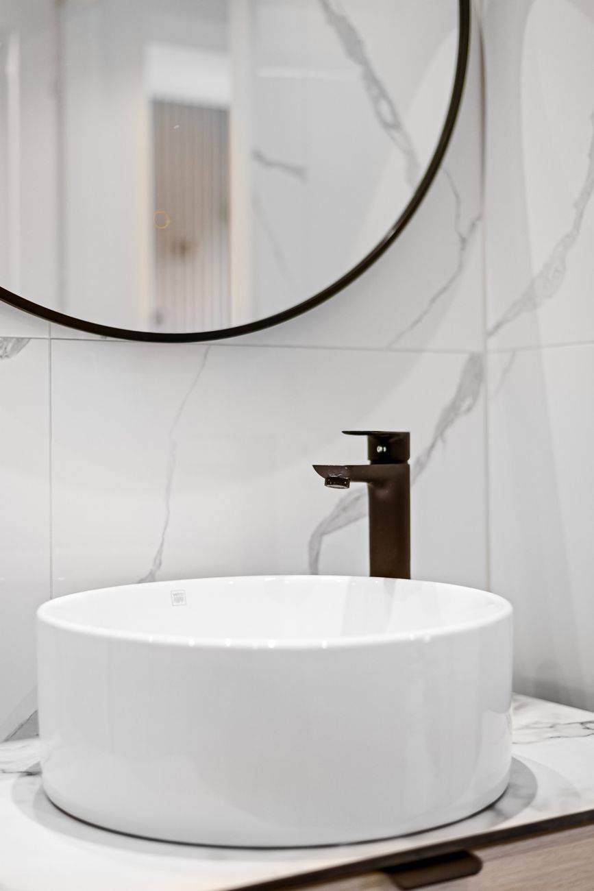 A stylish minimalist bathroom setup featuring a round sink and sleek faucet.