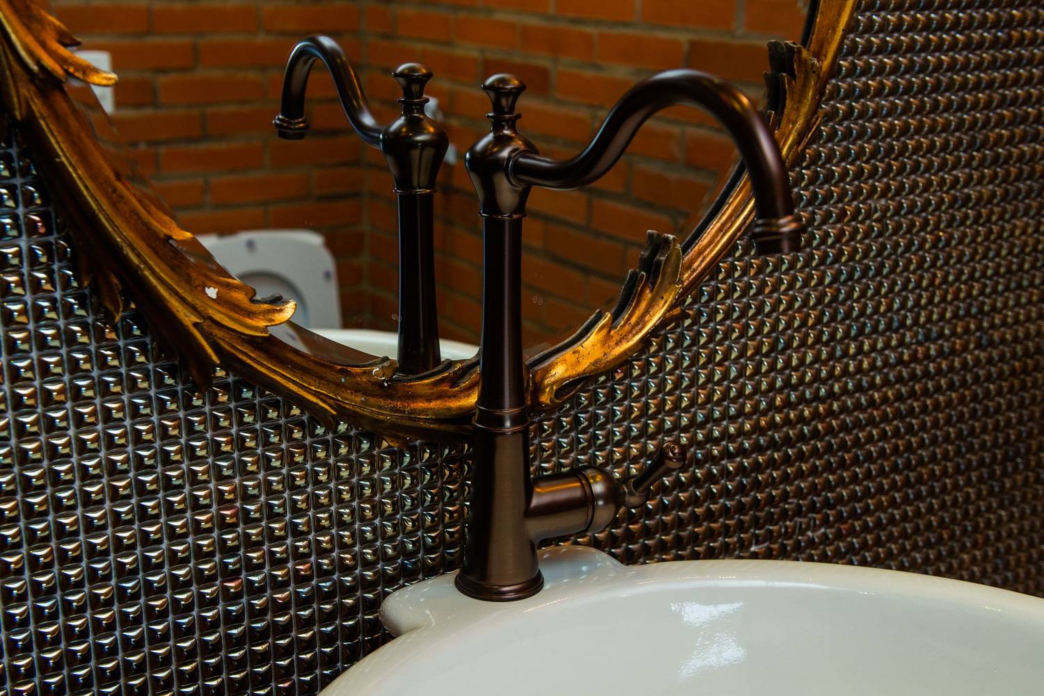 Close-up of a luxury bathroom faucet with an ornate mirror reflecting intricate details.