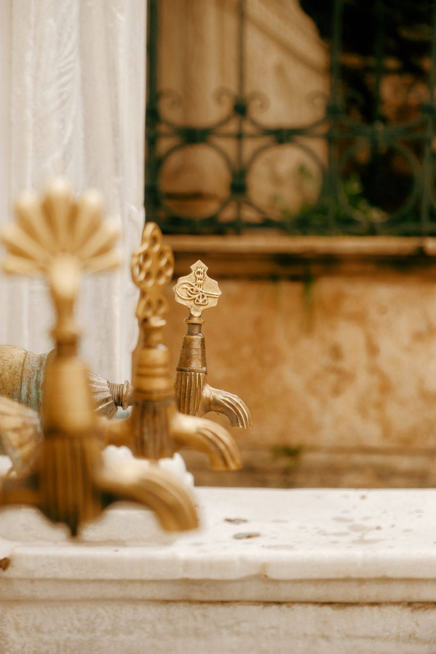 Close-up of ornate brass taps on an antique marble fountain with decorative patterns.