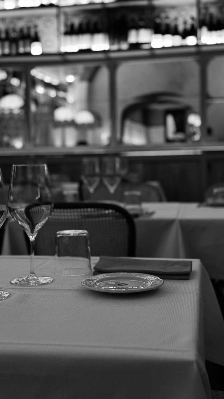 Monochrome image of a sophisticated restaurant table setting with wine glasses.