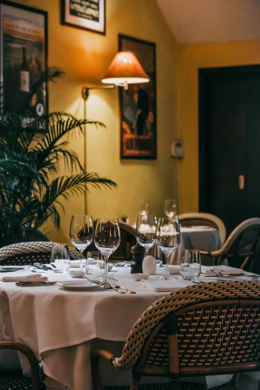 Cozy restaurant interior with elegantly set table under warm lighting, perfect for dining ambiance.