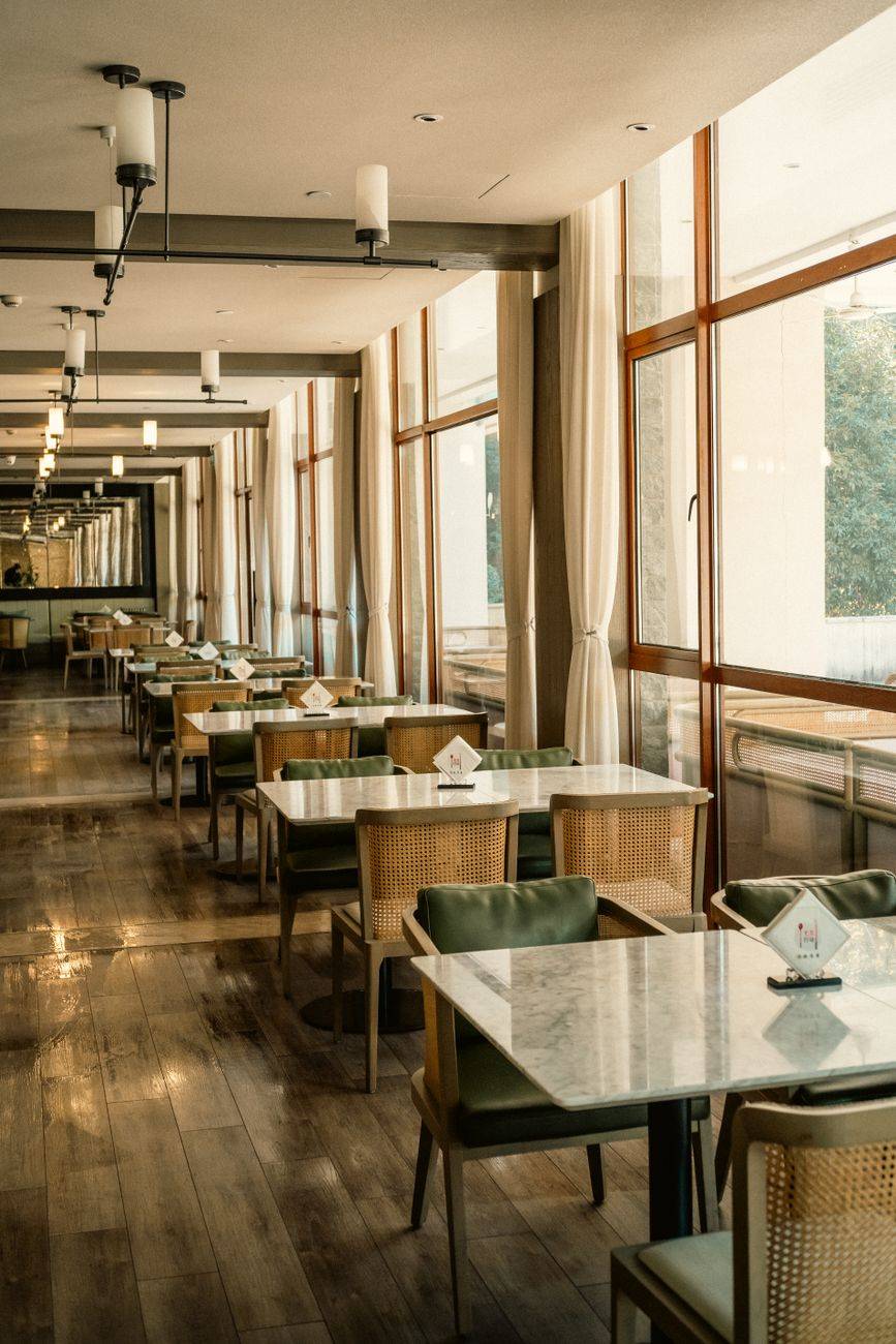 A serene hotel dining space with natural light streaming through large windows.