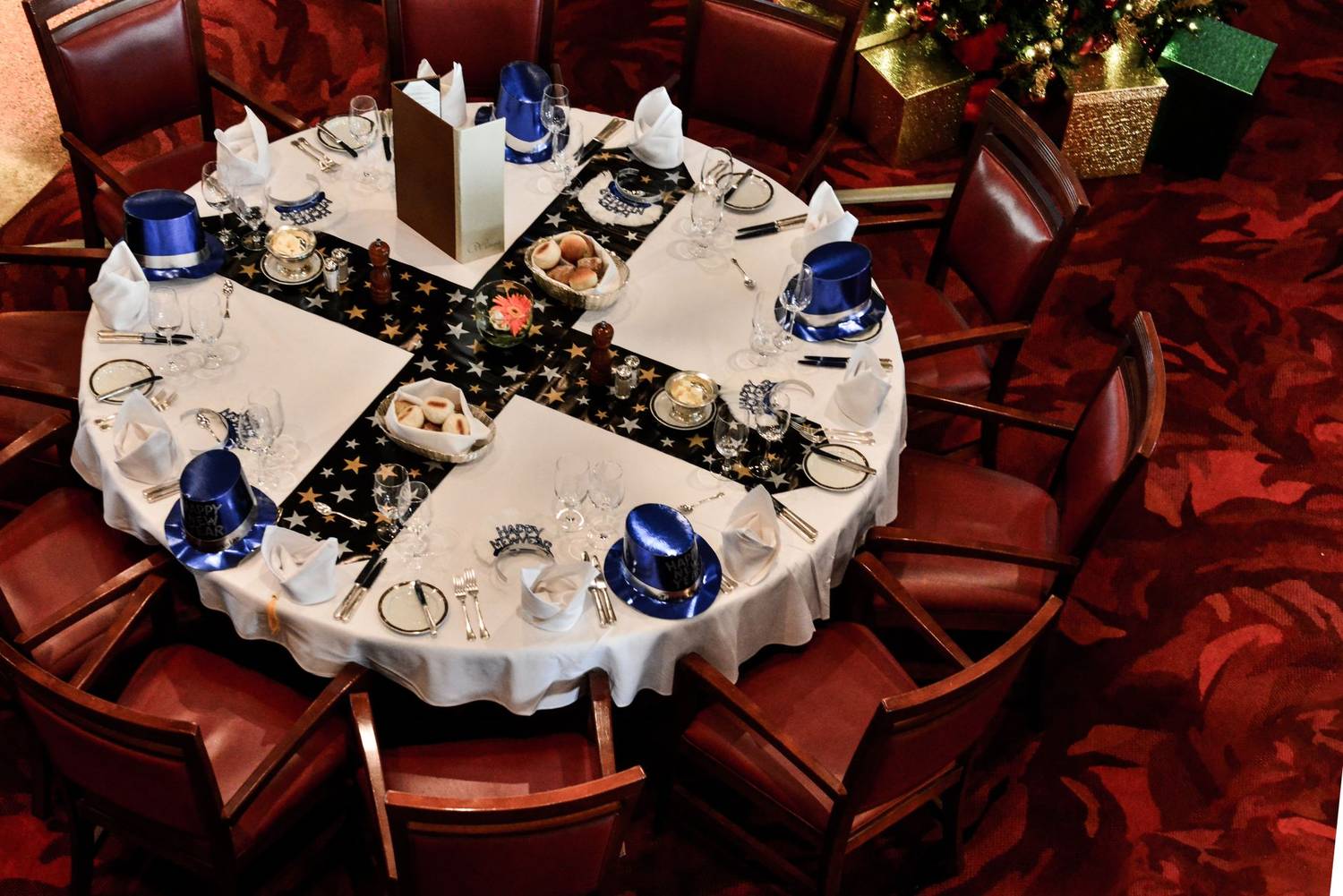 Aerial view of a beautifully decorated festive dinner table with blue hats and star-themed decor, set for celebration.
