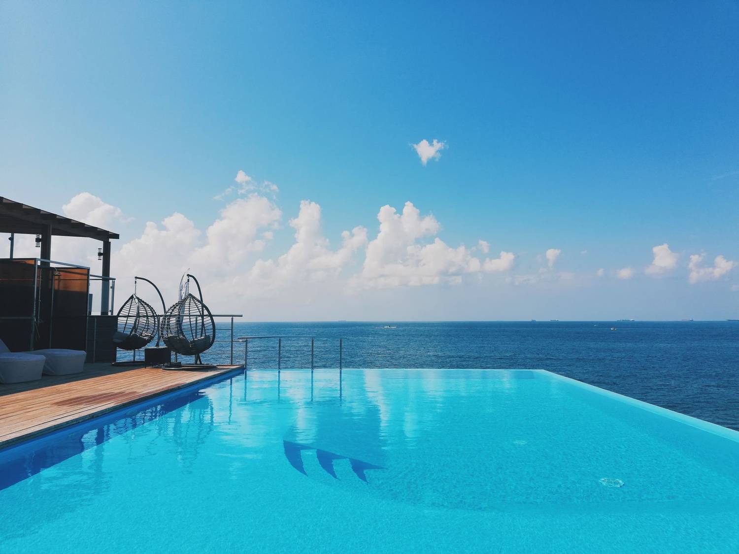 Relax at a scenic infinity pool with ocean views and hanging chairs.