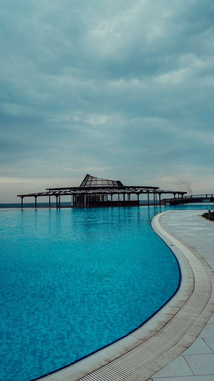Serene infinity pool with tropical vibes at a luxurious resort under cloudy skies.