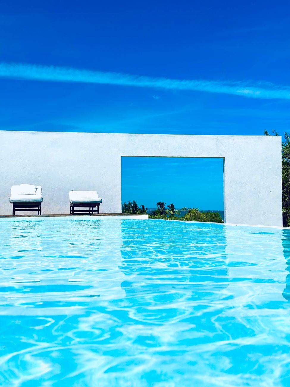 A serene poolside view with clear blue skies and modern architecture, perfect for relaxation.