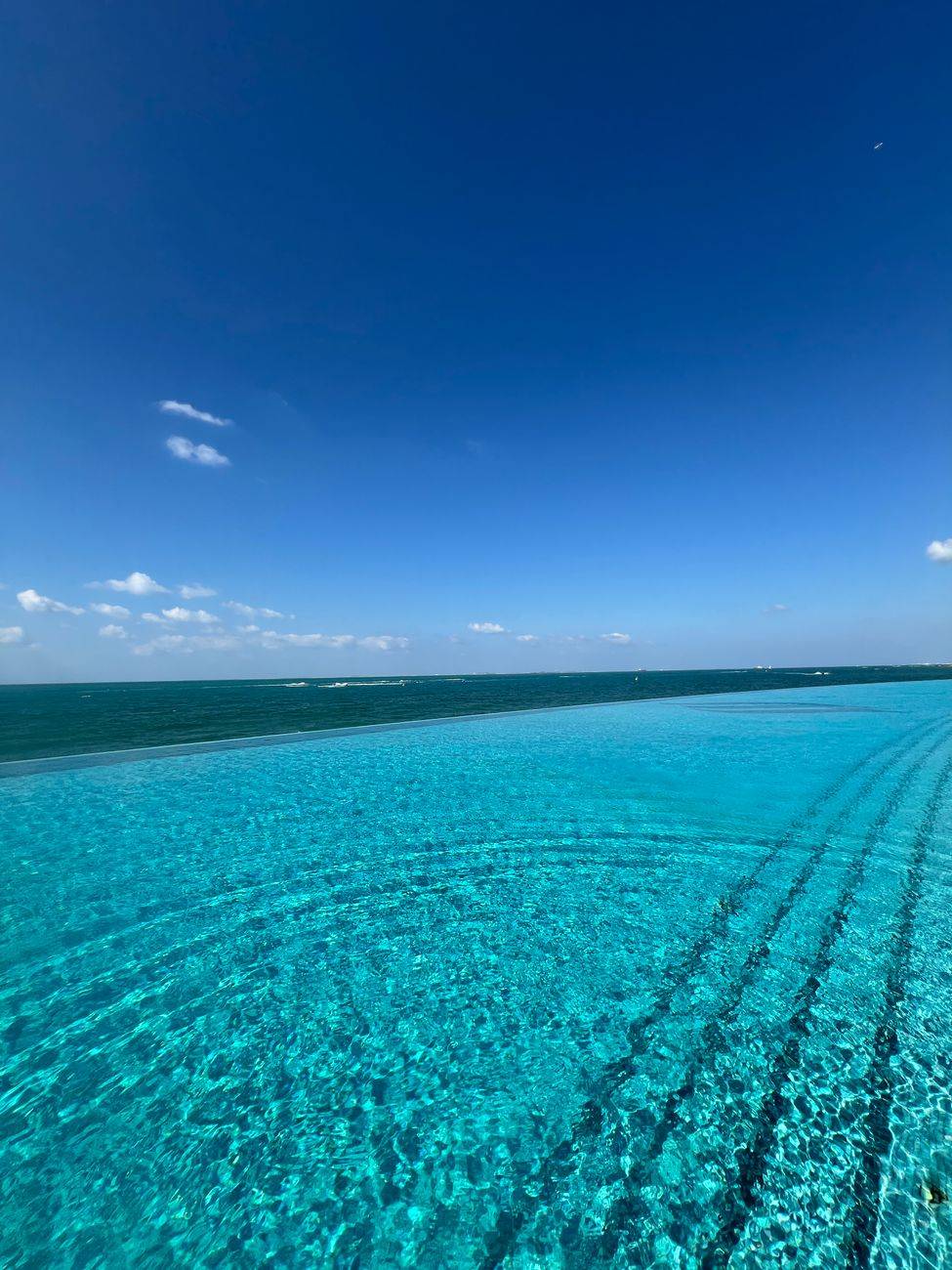 Idyllic view of an infinity pool blending into the ocean on a sunny day.