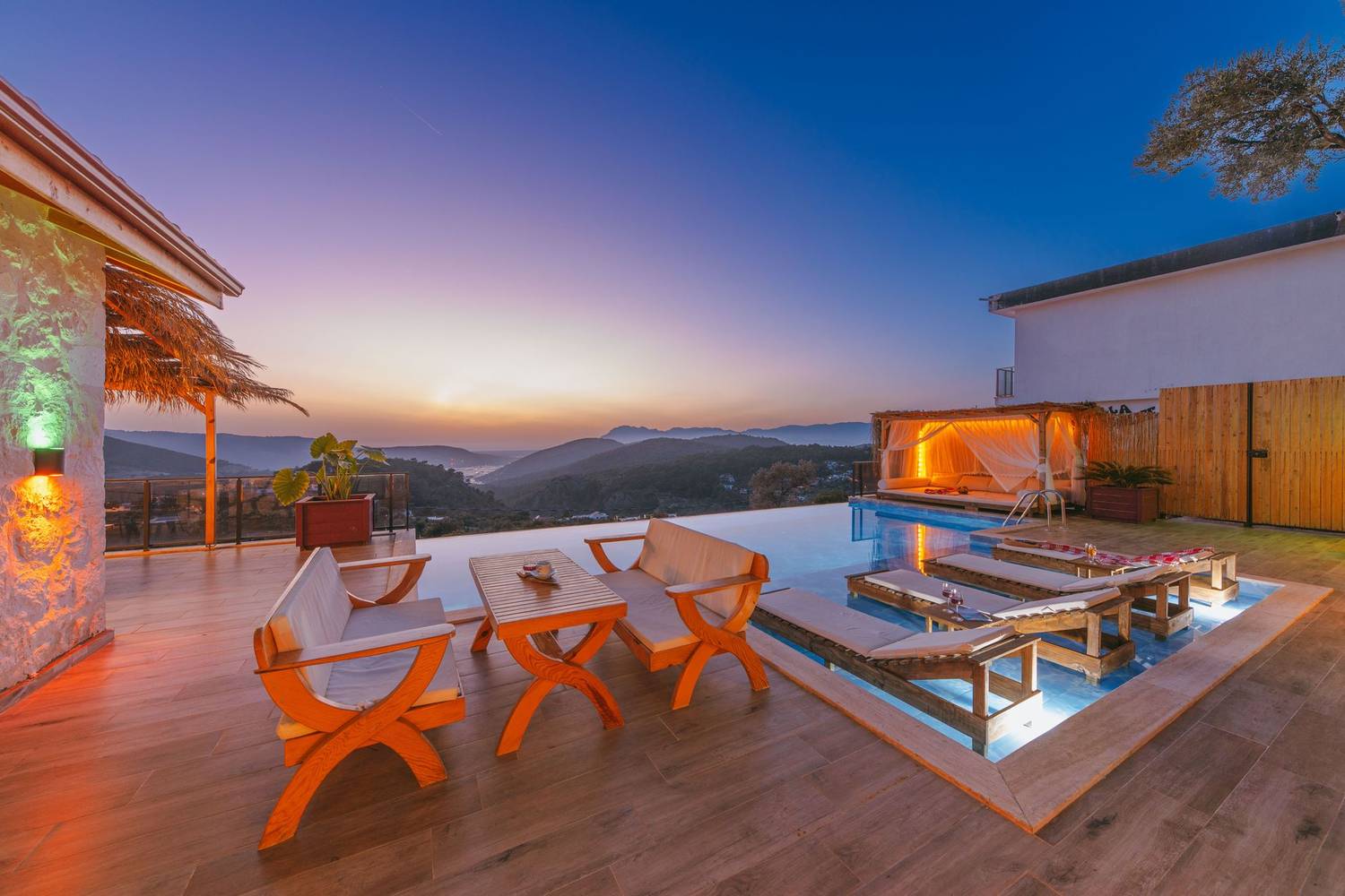 Stunning villa patio with infinity pool and mountains at sunset, perfect for a luxurious escape.