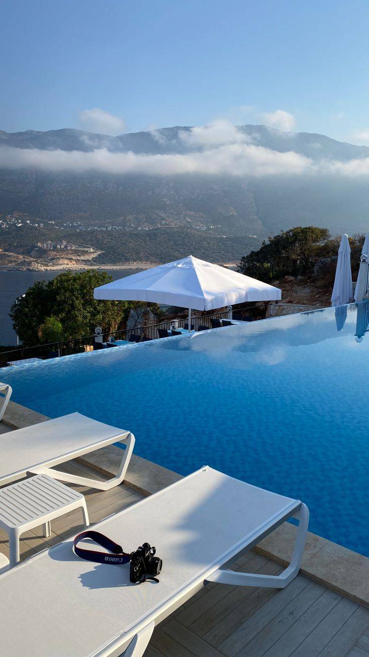Gorgeous infinity pool with lounge chairs and umbrellas, overlooking the stunning Kaş coastline in Turkey.
