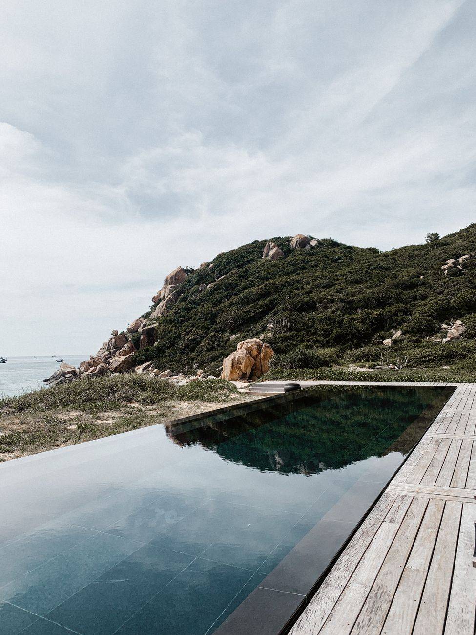 Tranquil infinity pool with stunning ocean and mountain view, perfect travel destination.