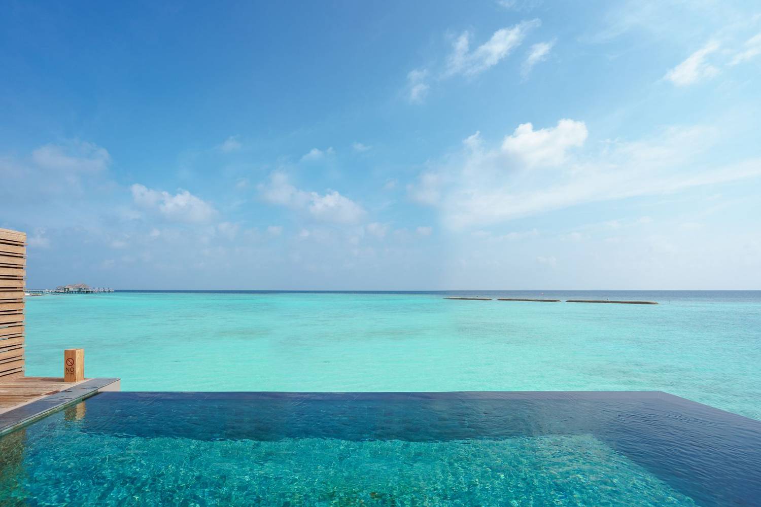 Infinity pool with breathtaking views of turquoise ocean under a bright blue sky.
