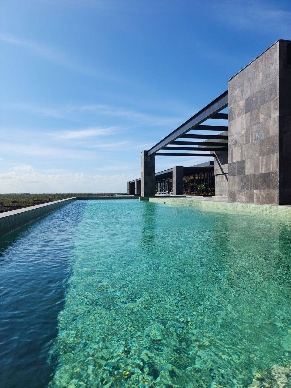 Elegant infinity pool reflecting the blue sky and contemporary architecture, perfect for luxury travel themes.