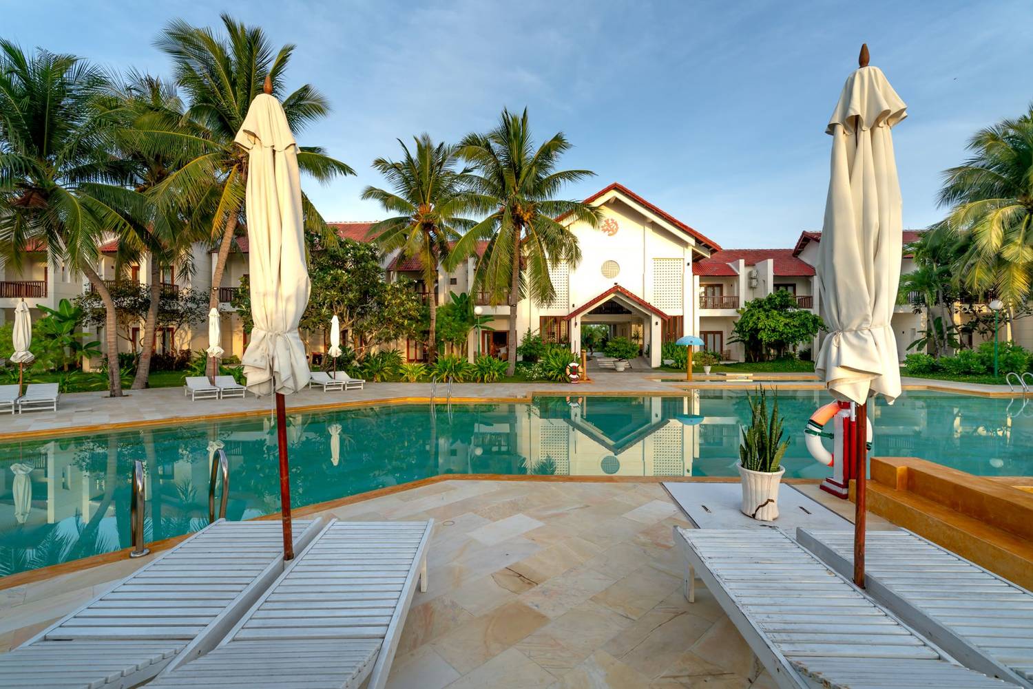 Tranquil luxury resort showcasing a serene pool, palm trees, and elegant architecture for a relaxing vacation.