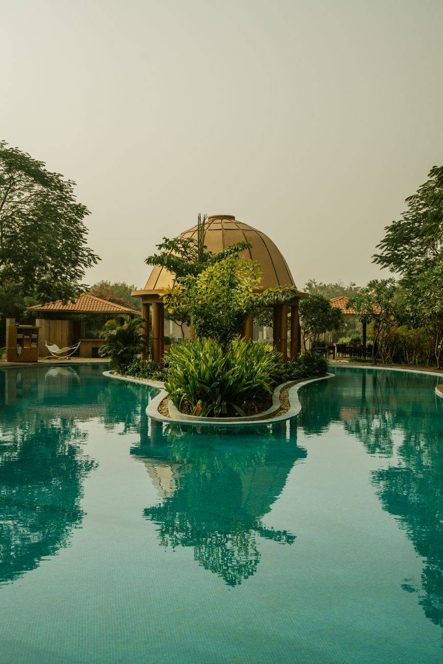 A tranquil view of a luxury resort with a pavilion and pool in India.