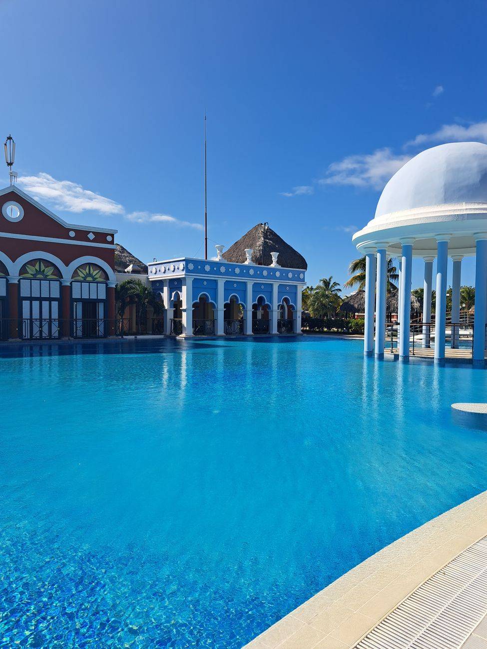 Experience luxury at a vibrant resort in Varadero, featuring a stunning turquoise pool under a clear sky.