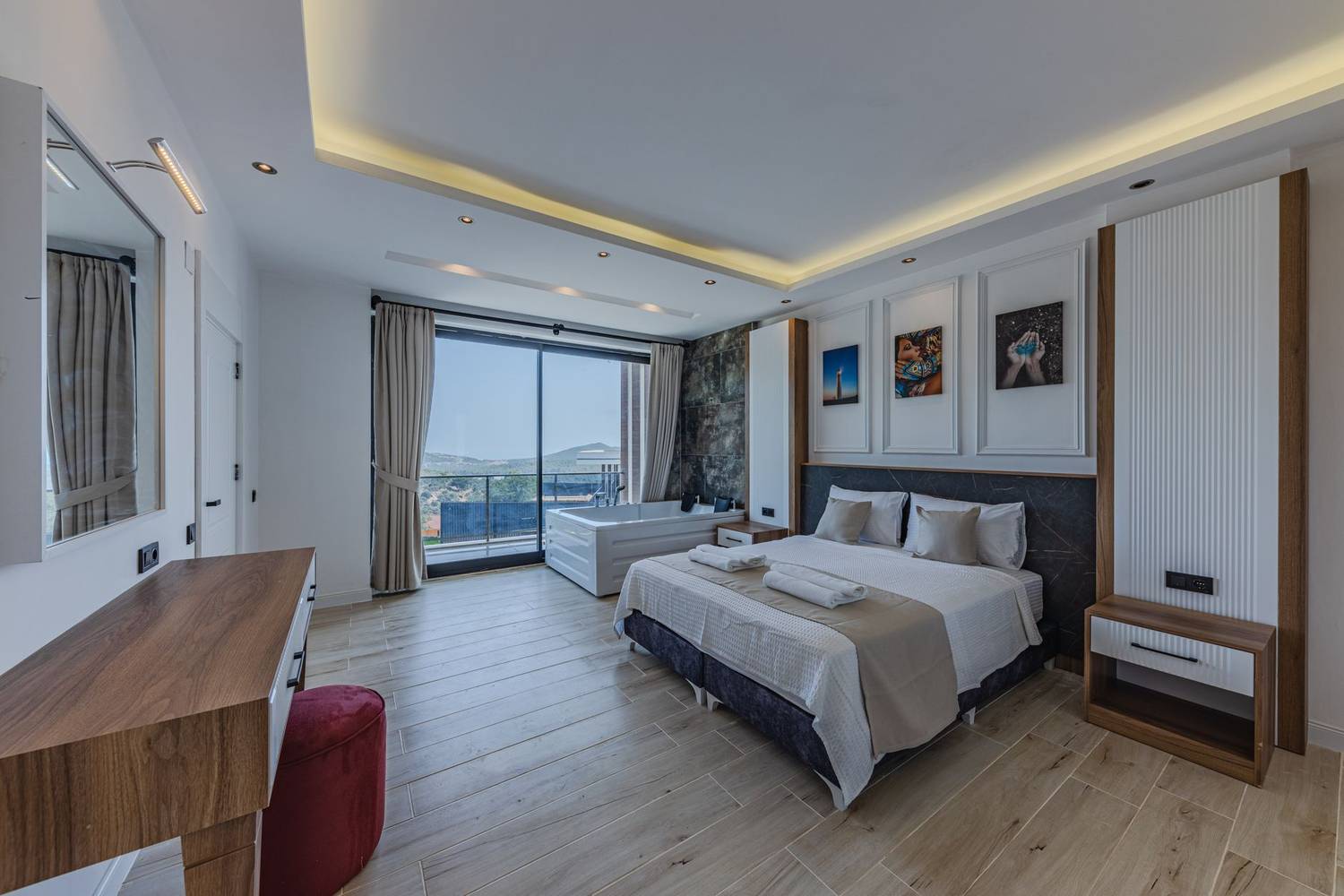 Modern hotel room with a large bed, hot tub, and scenic balcony view.
