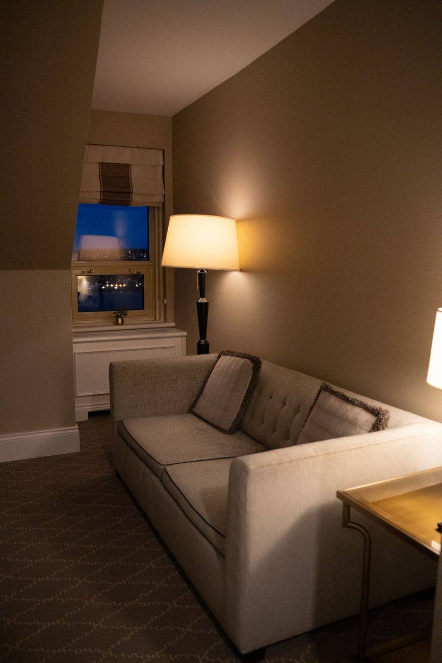 Warmly lit hotel room with a sofa and city view ideal for relaxation in Québec.