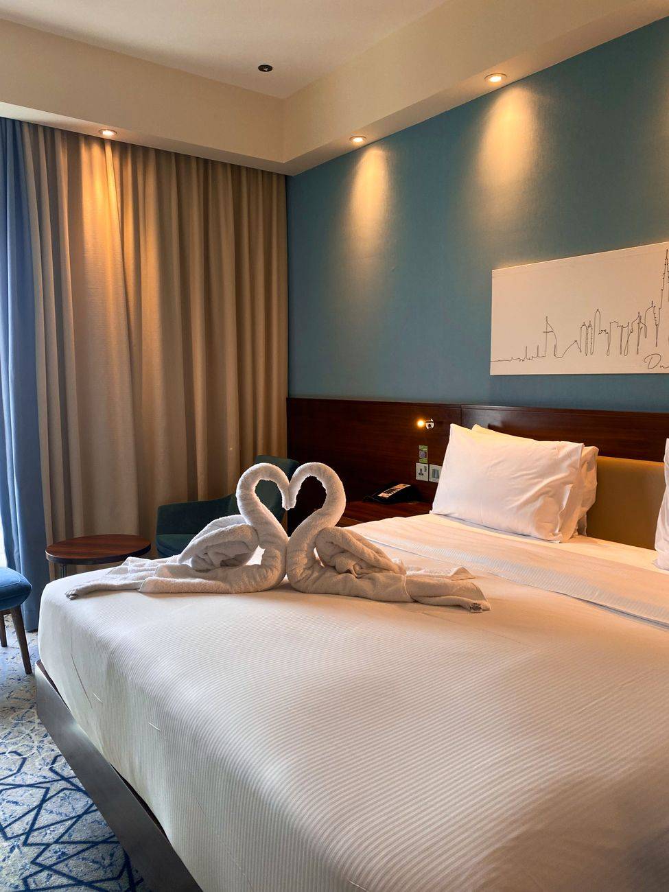 Luxurious hotel room in Dubai featuring elegant swan towels on a king-sized bed.
