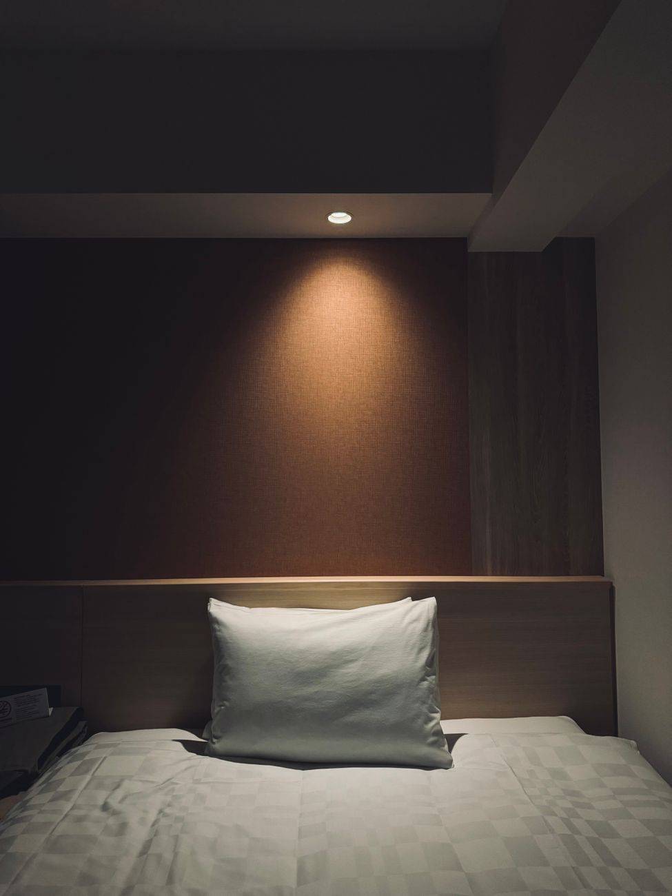 A softly lit, minimalist bedroom interior in Takayama, Japan, featuring cozy bed linen and design.