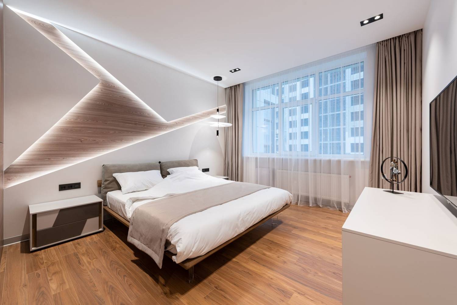 Bright hotel room interior with soft white bed and wooden floor near cupboard and TV near window with curtains