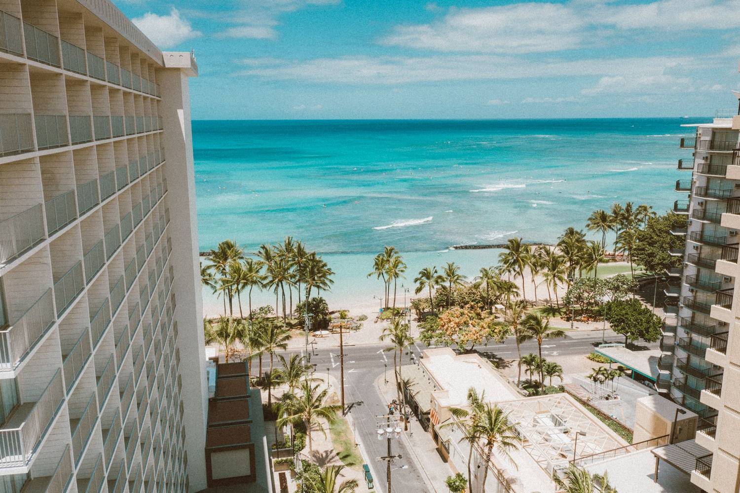 Breathtaking view of Waikiki Beach and palm trees from a hotel balcony in Honolulu, Hawaii.