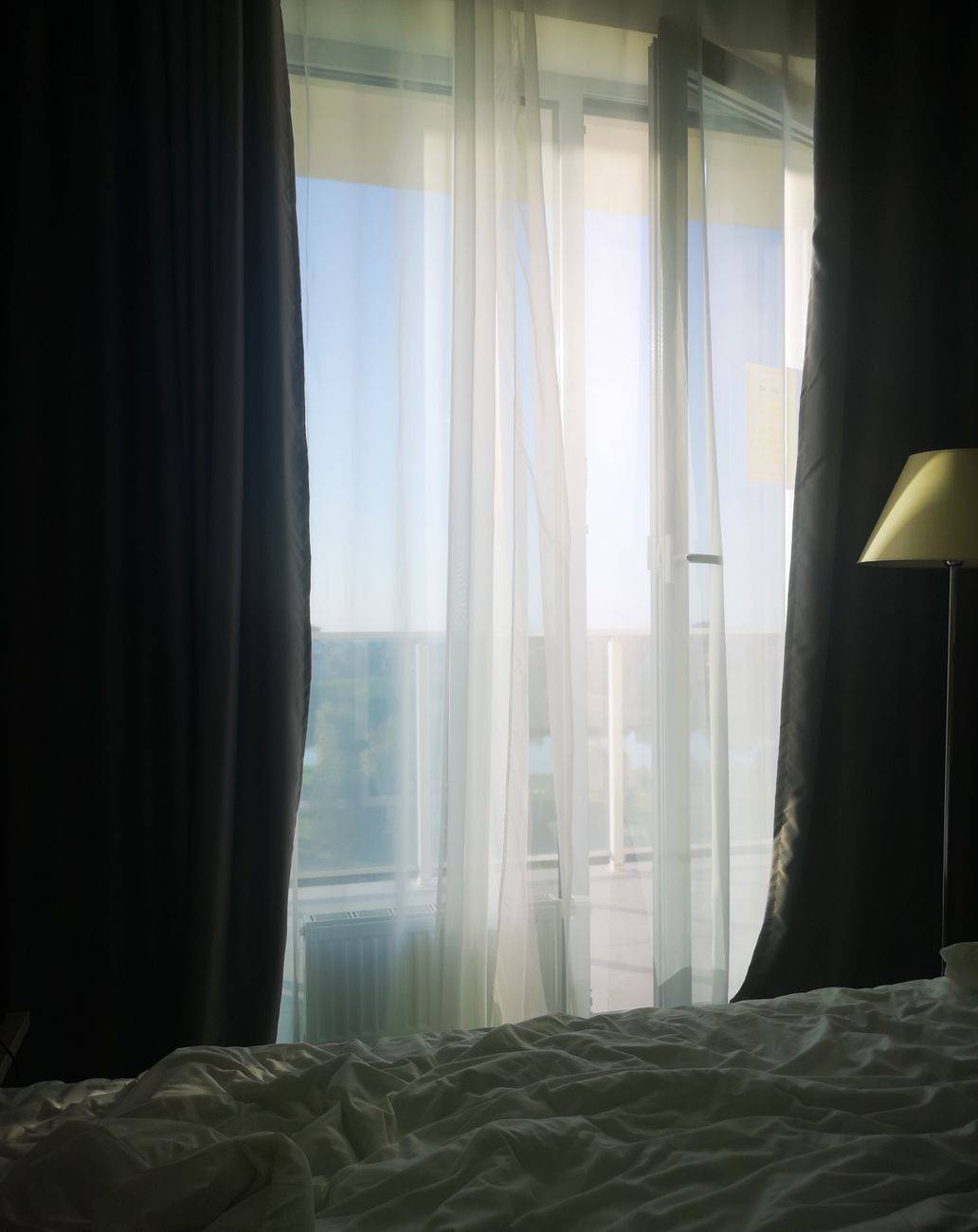 Sunlight pours through sheer curtains in a cozy hotel room, creating a relaxing ambiance.