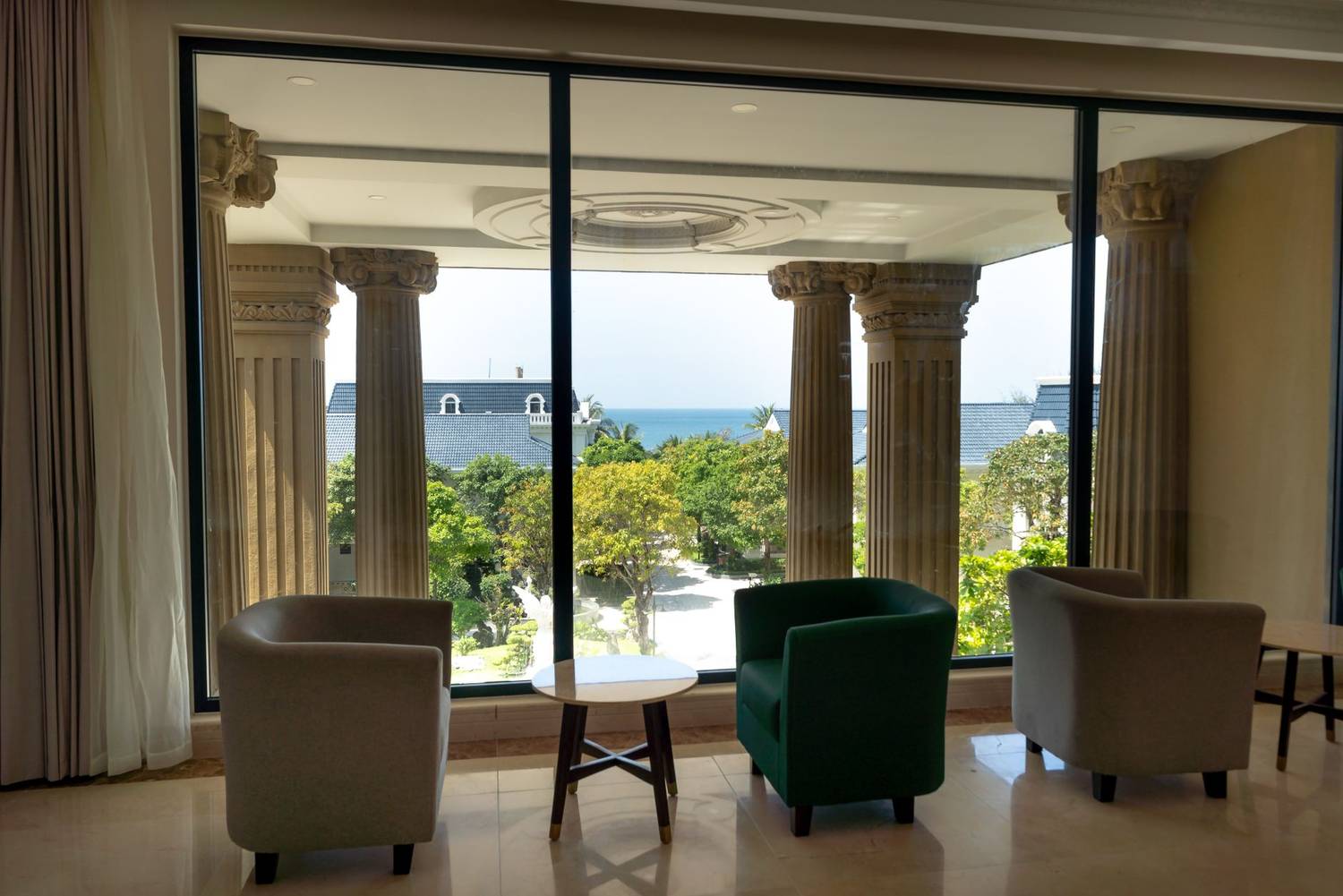 Chic interior with armchairs, facing picturesque ocean view through classic columns.