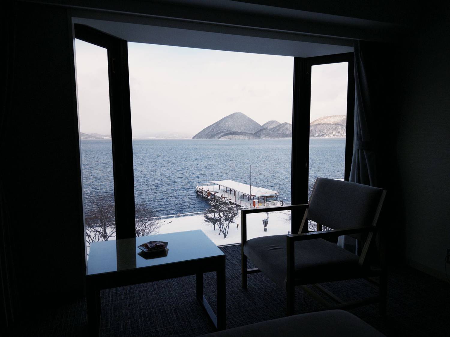 A beautiful winter view of Lake Toya from a cozy room with open window.
