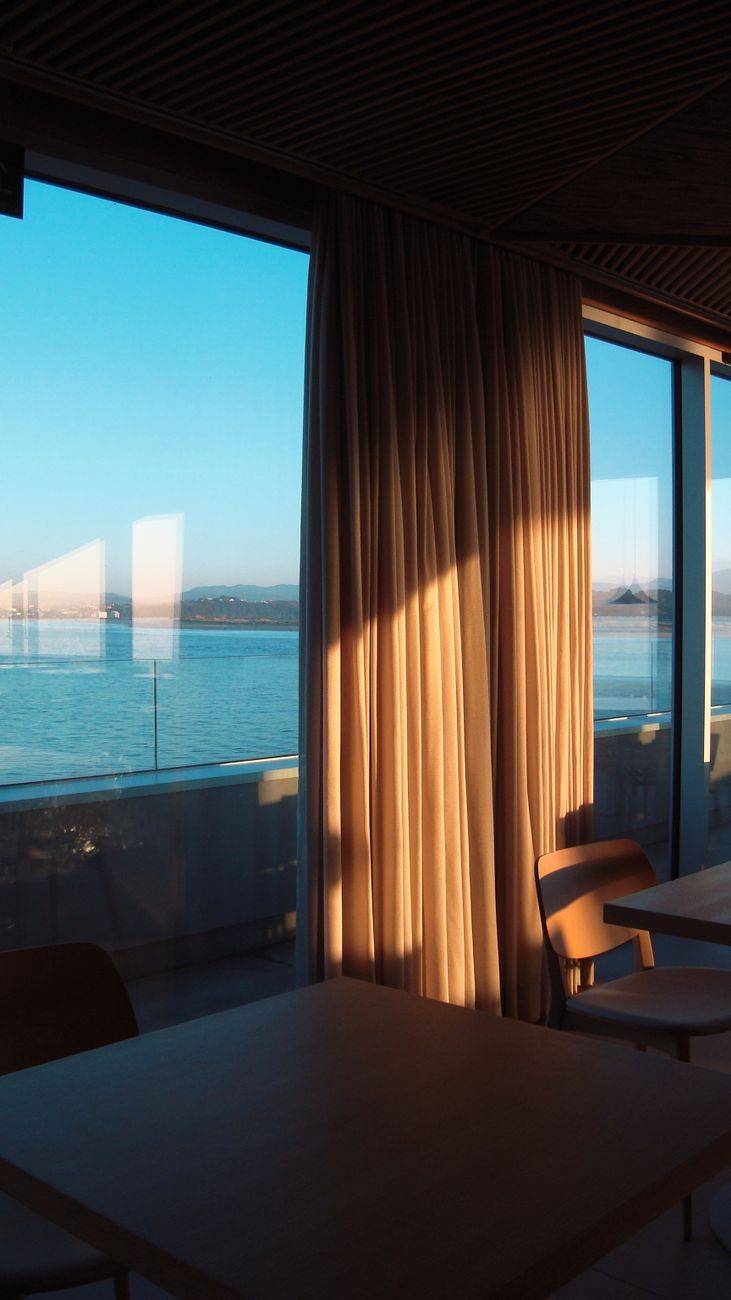 Elegant hotel room window view with curtains open to a scenic seaside landscape in Santander, Spain.