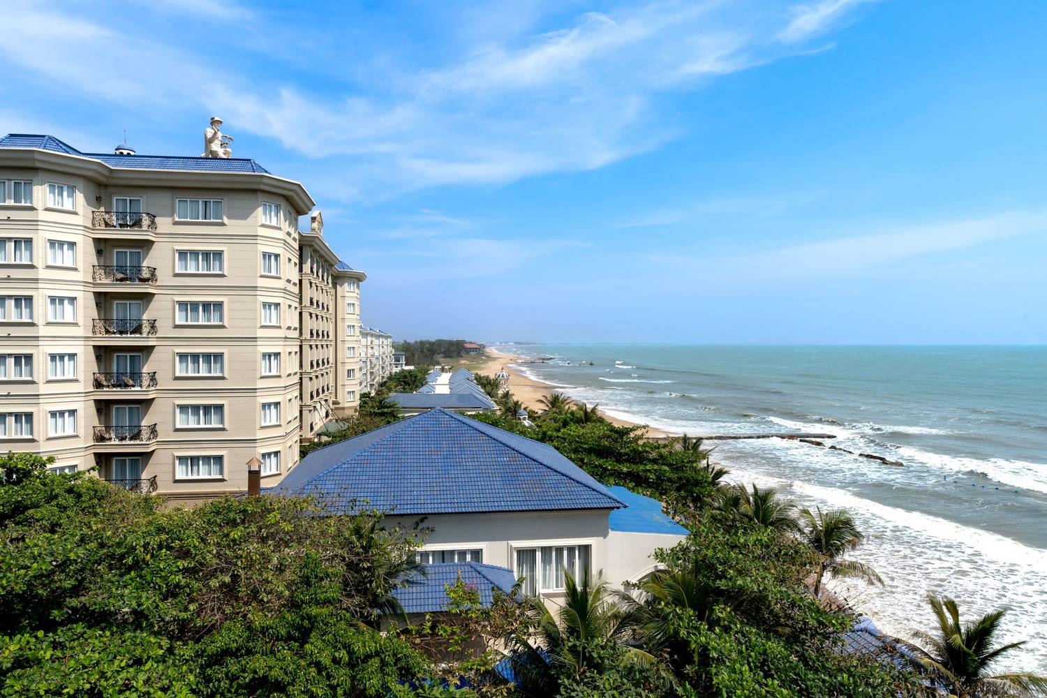 A luxurious beachfront resort overlooking the ocean with clear blue skies and sandy beaches.